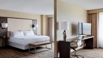Habitación de hotel con cama, escritorio, silla y televisor.