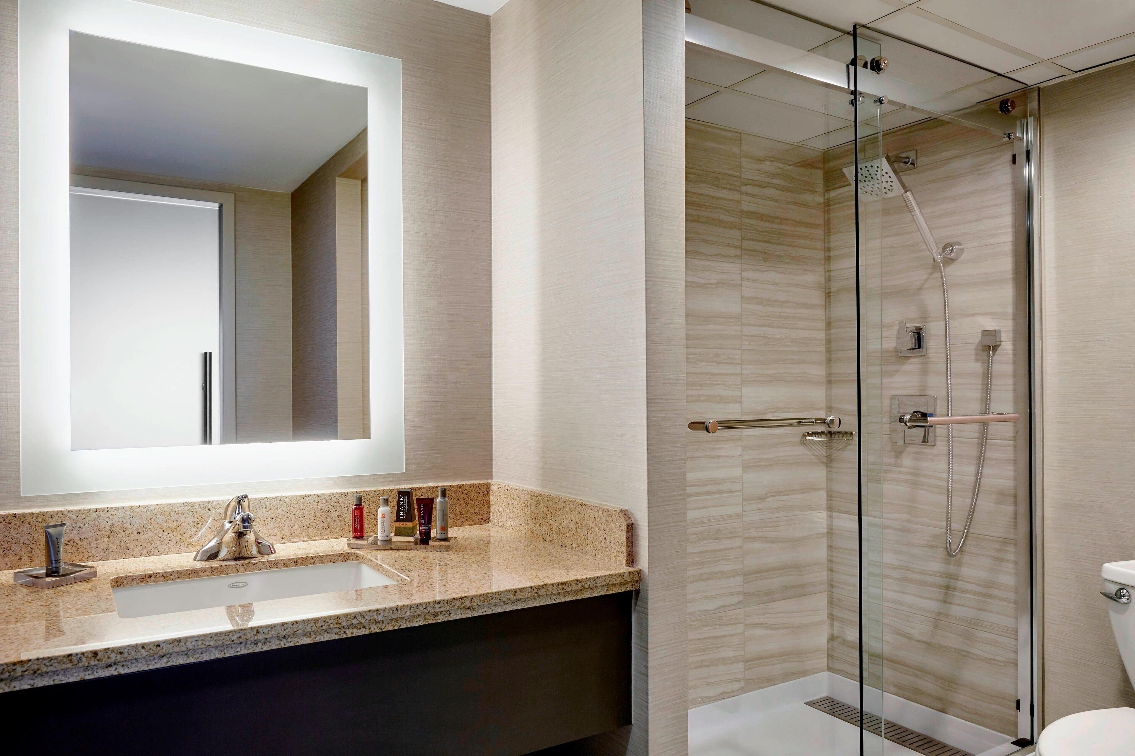Un baño moderno con un espejo grande, un lavabo y una ducha con mampara de vidrio.