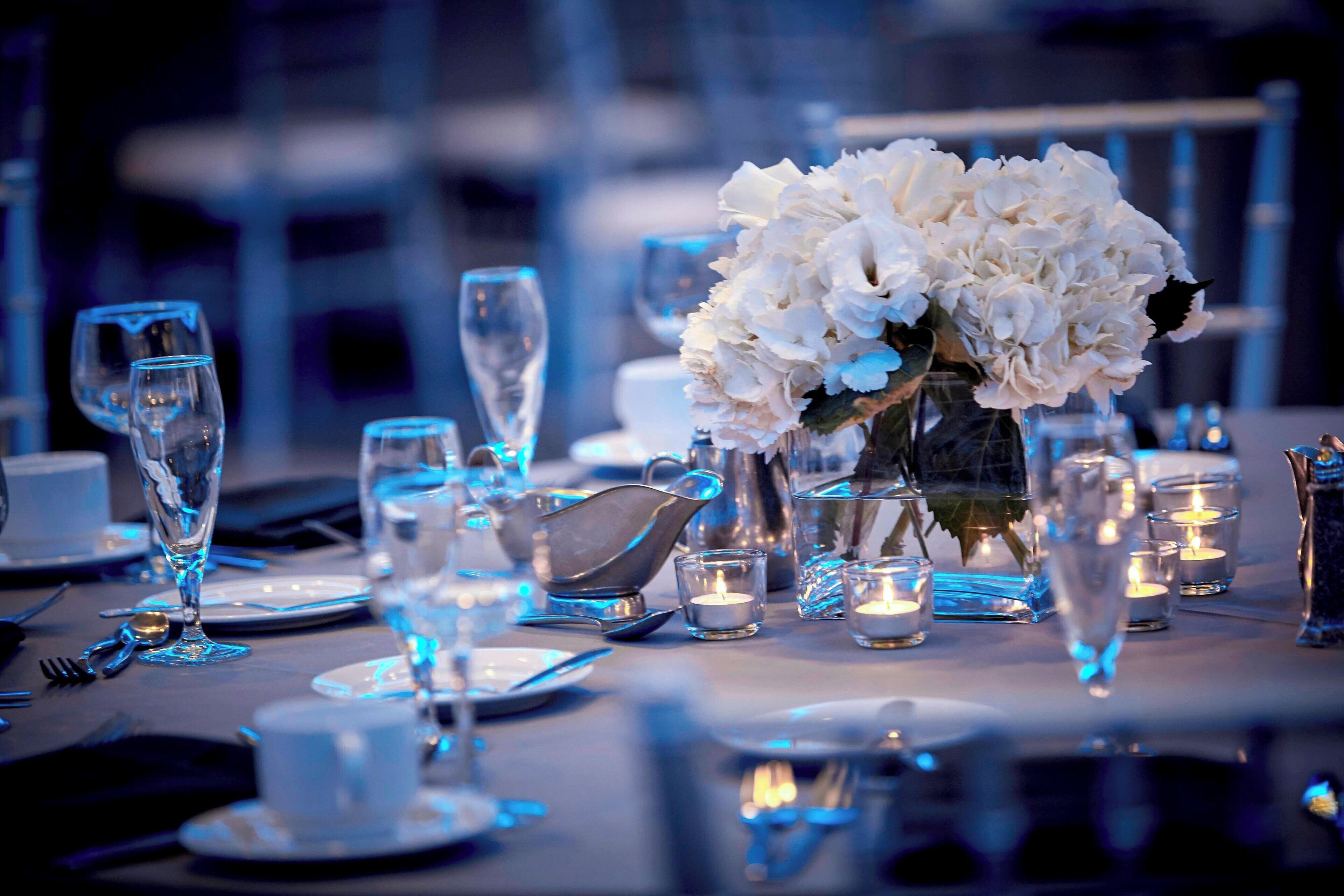 A table set for a formal dinner with clear glassware, white flowers, and candles.