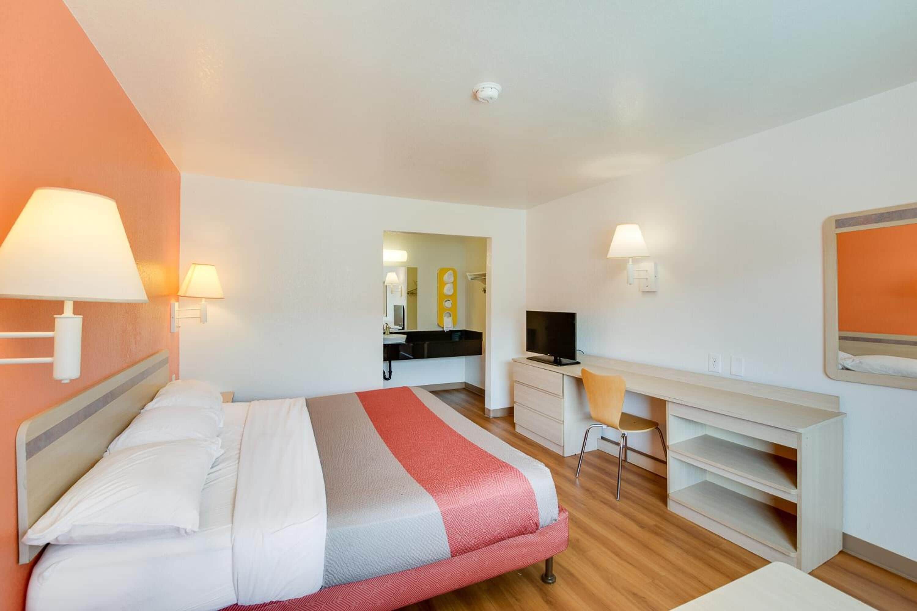 Une chambre d’hôtel équipée d’un lit, d’un bureau, d’une chaise et d’un téléviseur.