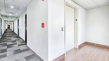 A hotel hallway with carpeted flooring, white walls, and a door marked with the number 3.