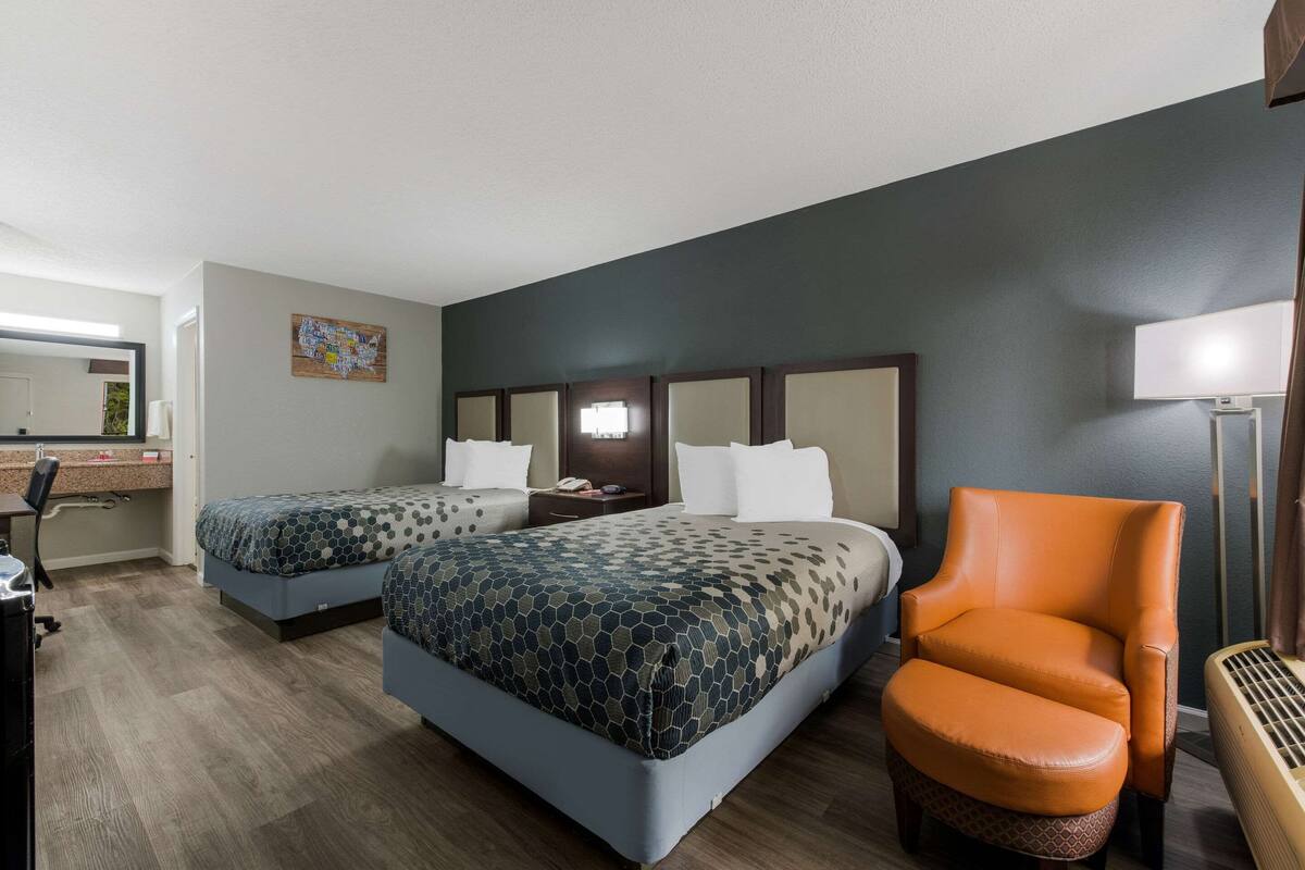 Ein Hotelzimmer mit zwei Betten, einem Schreibtisch, einem Stuhl und einem Nachttisch.