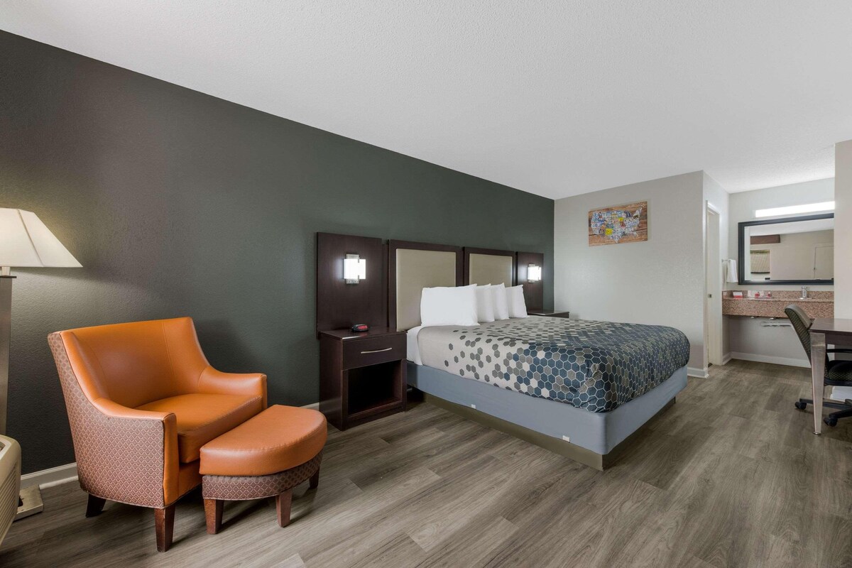 A hotel room with a bed, a chair, a desk, and a nightstand.
