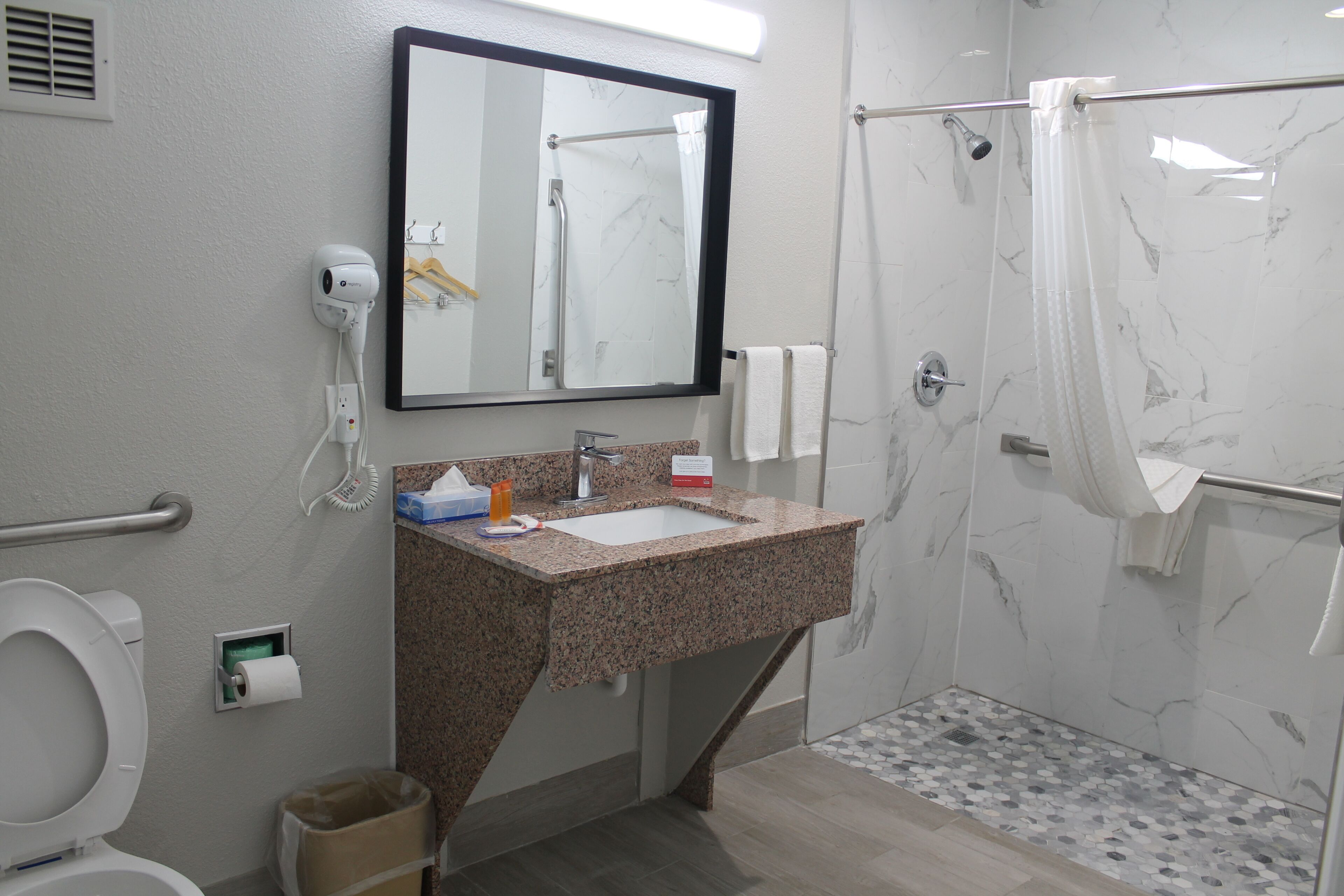 Ein Badezimmer mit Waschbecken, Spiegel, Toilette und Dusche.