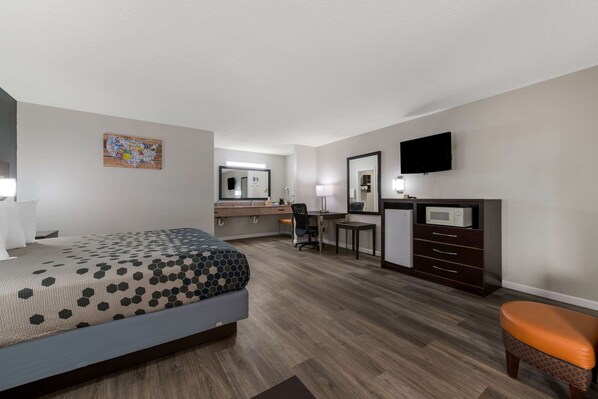 Una habitación de hotel con cama, escritorio, silla, cómoda y televisor.