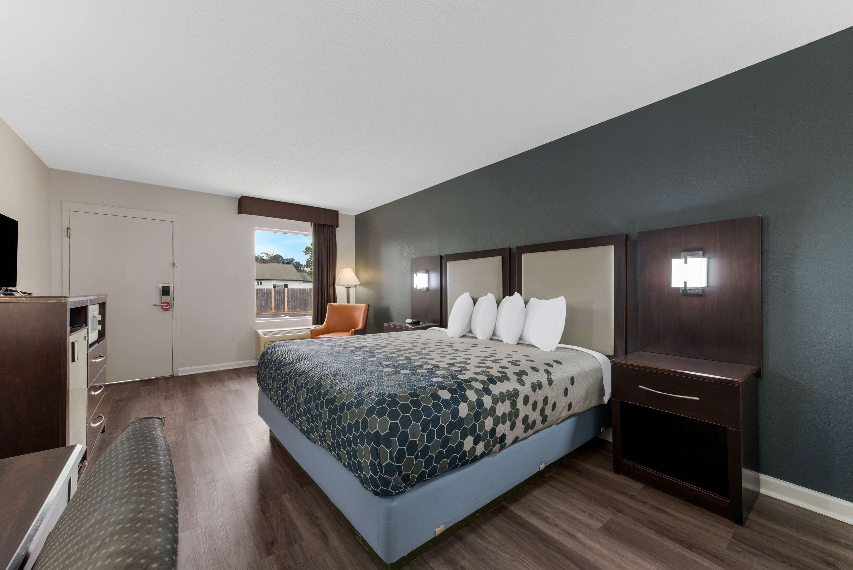 Habitación de hotel con una cama grande, un escritorio, una silla y una ventana con vistas.