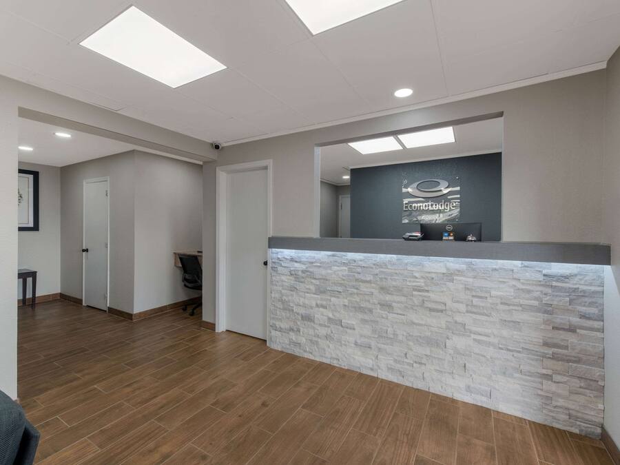 A reception area with a stone-textured counter, recessed ceiling lights, and a door leading to another room.
