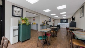 Un restaurante espacioso con techos altos, iluminación empotrada y una zona de cocina.
