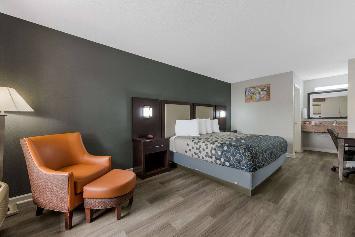 Ein Hotelzimmer mit Bett, Sessel, Schreibtisch und Lampe.