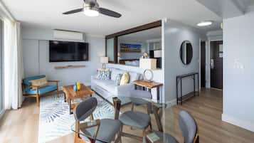 Un salon moderne comprenant un canapé, des fauteuils, une table basse, un téléviseur et un ventilateur de plafond.