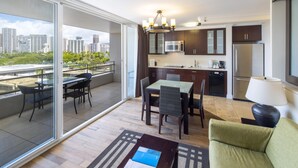 A modern apartment with a balcony, dining area, kitchen, and a view of the city skyline. - Regency on Beachwalk Waikiki by OUTRIGGER (Honolulu)