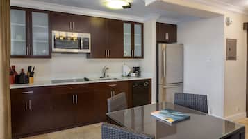 A modern kitchen with dark wooden cabinets, stainless steel appliances, and a glass dining table.