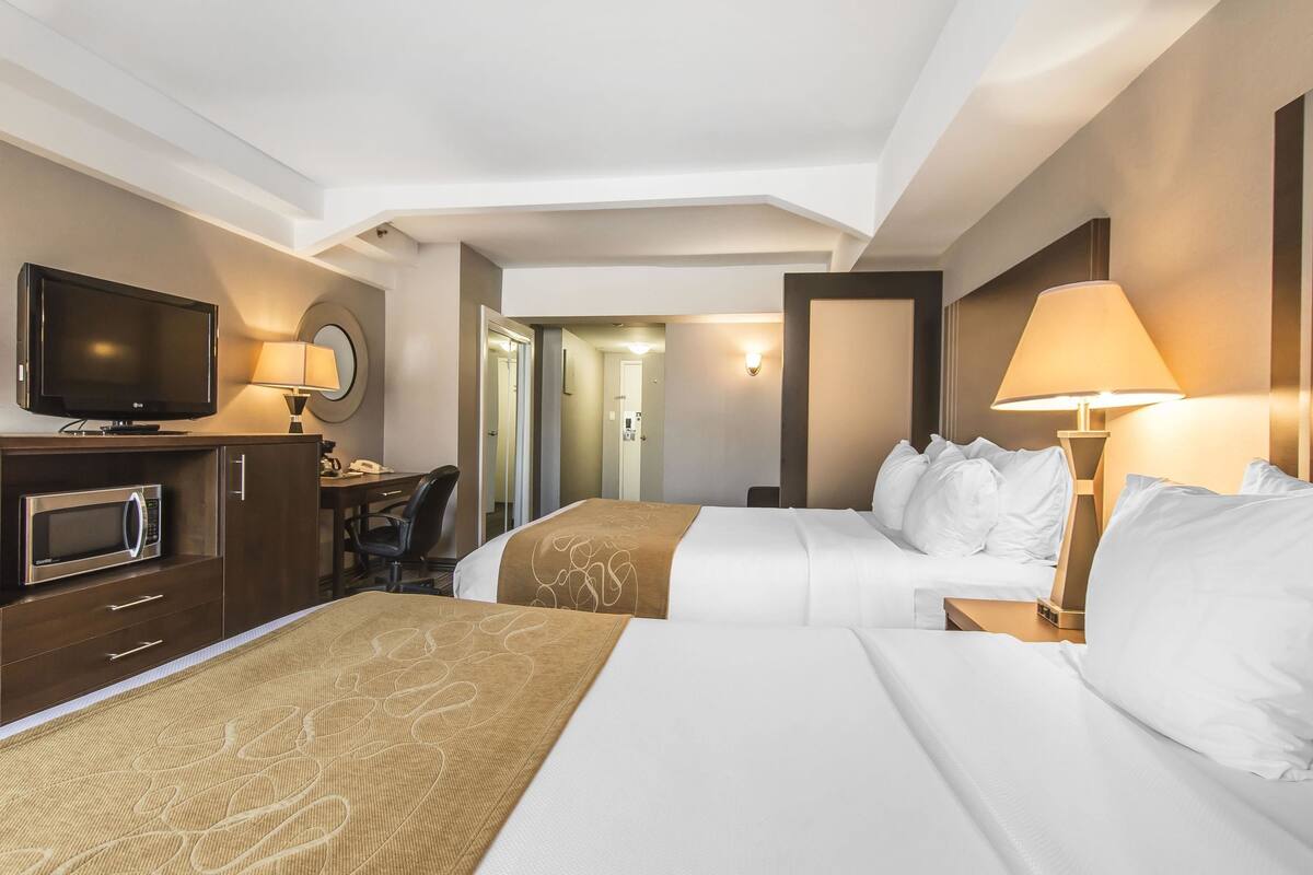 Habitación de hotel con dos camas, un escritorio, televisor y microondas.