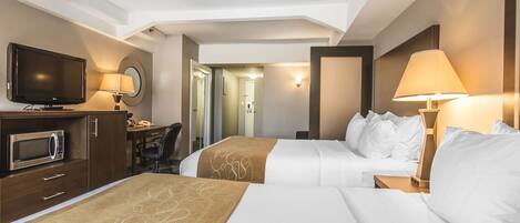 A hotel room with two beds, a desk, a television, and a microwave.