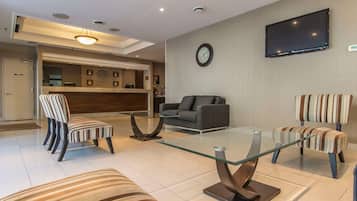 Una sala de estar moderna con sillas a rayas, una mesa de centro de vidrio, un sofá y un televisor de pantalla plana montado en la pared.