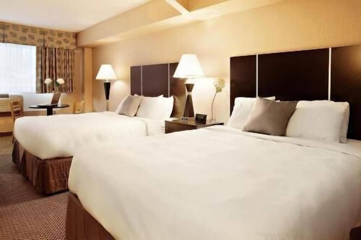 Une chambre d’hôtel avec deux lits, un bureau et une chaise.