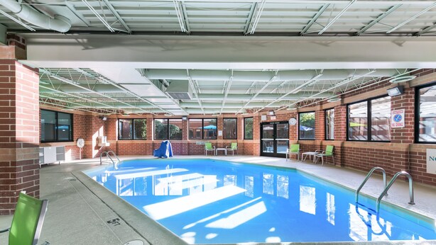 An indoor swimming pool with clear blue water, surrounded by brick walls and large windows. - Holiday Inn Express Naperville by IHG (Naperville)