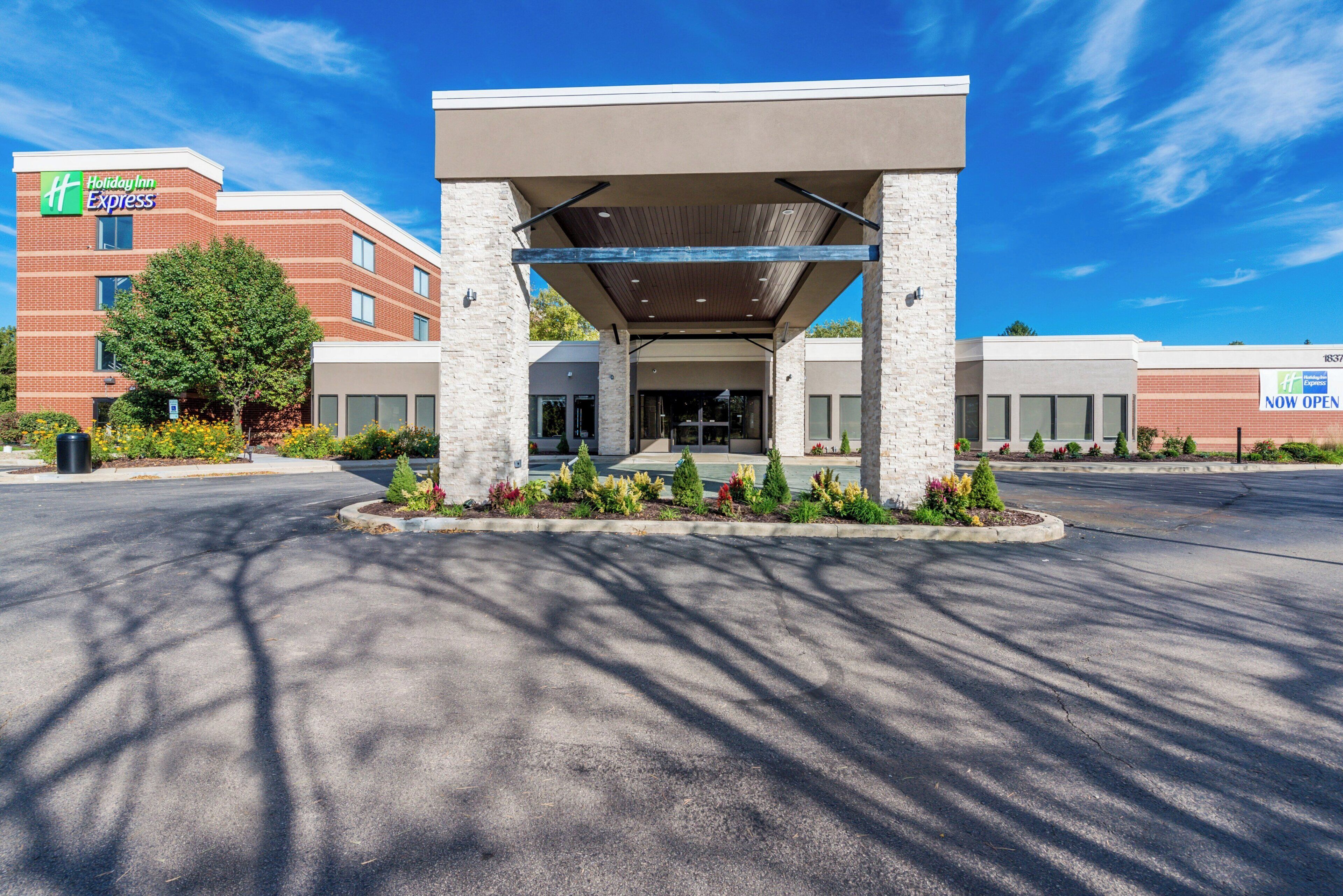 A Holiday Inn Express building with a covered entrance, brick facade, and landscaped garden area.