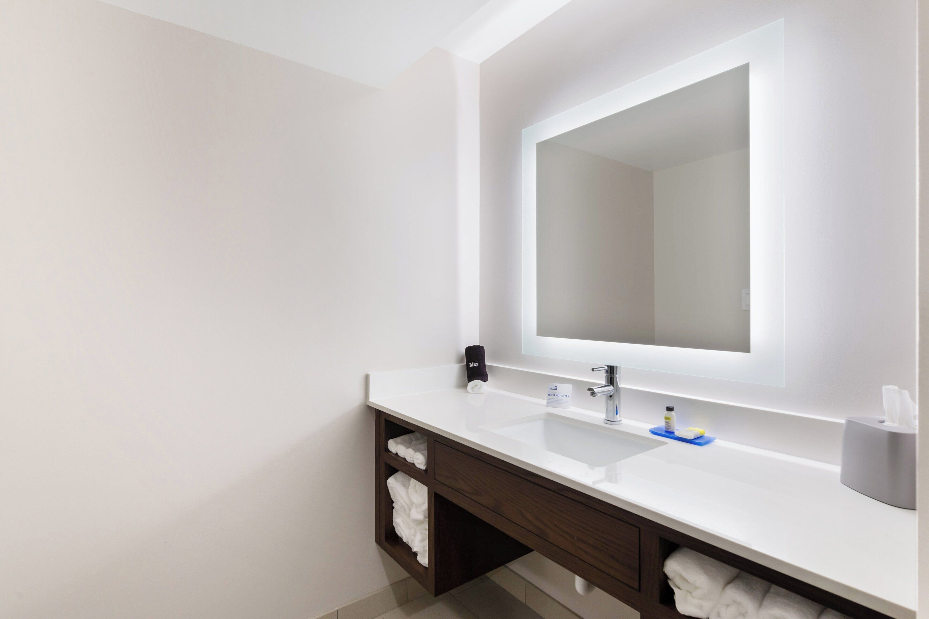 Une salle de bain moderne avec un grand miroir, deux lavabos et un porte-serviettes.
