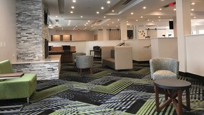 A hotel lobby with a modern design, featuring a stone accent wall, multiple seating areas, and a patterned carpet. - Holiday Inn Express Naperville by IHG (Naperville)