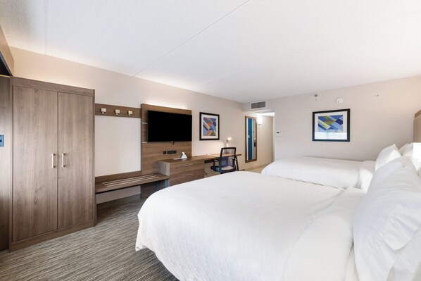 A hotel room with a large bed, a desk with a chair, a wardrobe, and a flat-screen TV.