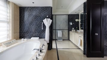 Een moderne badkamer met een groot bad, een wastafel met spiegel en een donkere marmeren wand.