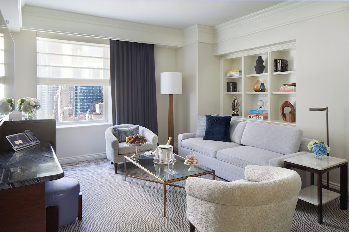 A modern living room with a sofa, armchairs, a coffee table, and a bookshelf.