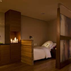 Relax in a serene space with a comfortable bed, elegant artwork, and a stylish cabinet.