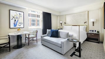 Et hotelværelse med seng, sofa, skrivebord og et vindue med gardiner.