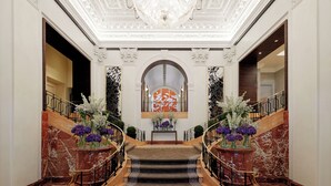Eine prachtvolle Lobby mit einer Marmortreppe, einem Chandelier und floralen Dekorationen.