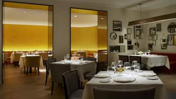 A restaurant with tables set for dining, a mirror wall, and a warm ambient light.