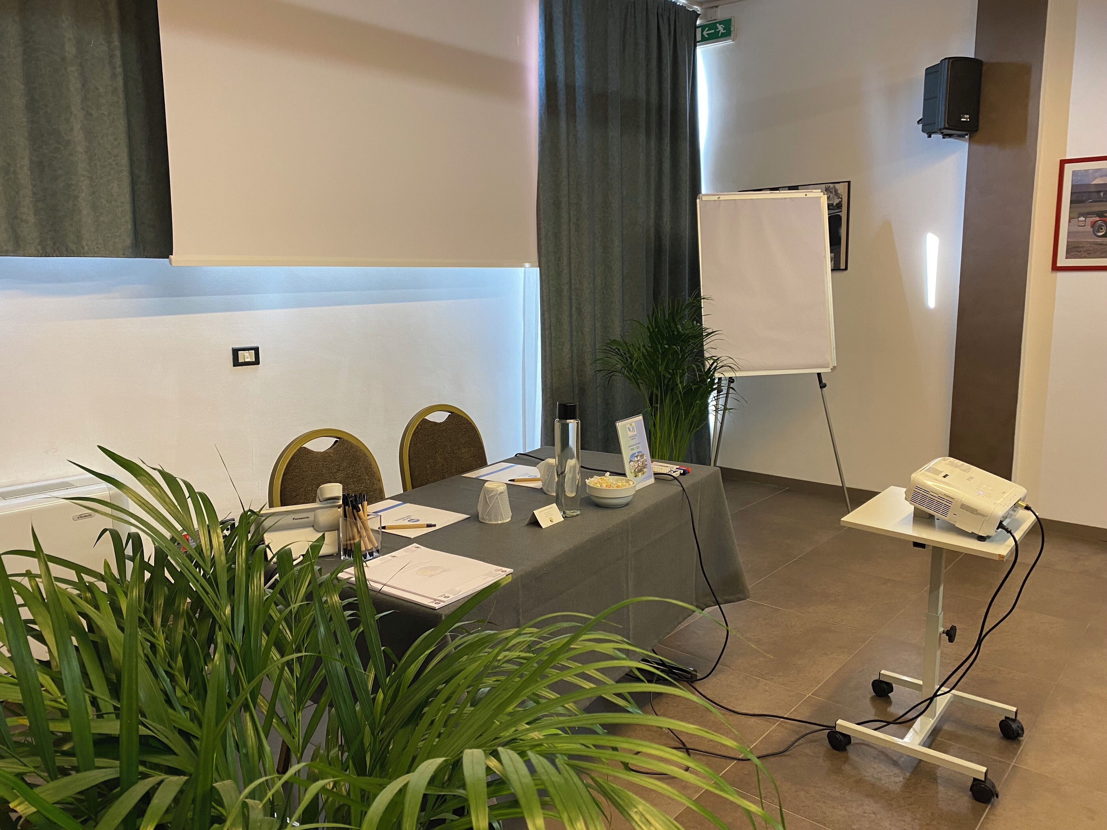 Een vergaderruimte met een tafel, stoelen, een beamer, een whiteboard en potplanten.