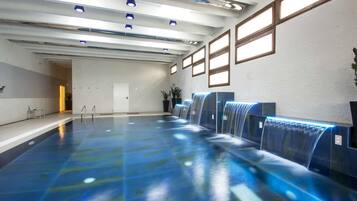 Un'ampia piscina interna con diverse fontane e illuminazione a sospensione.