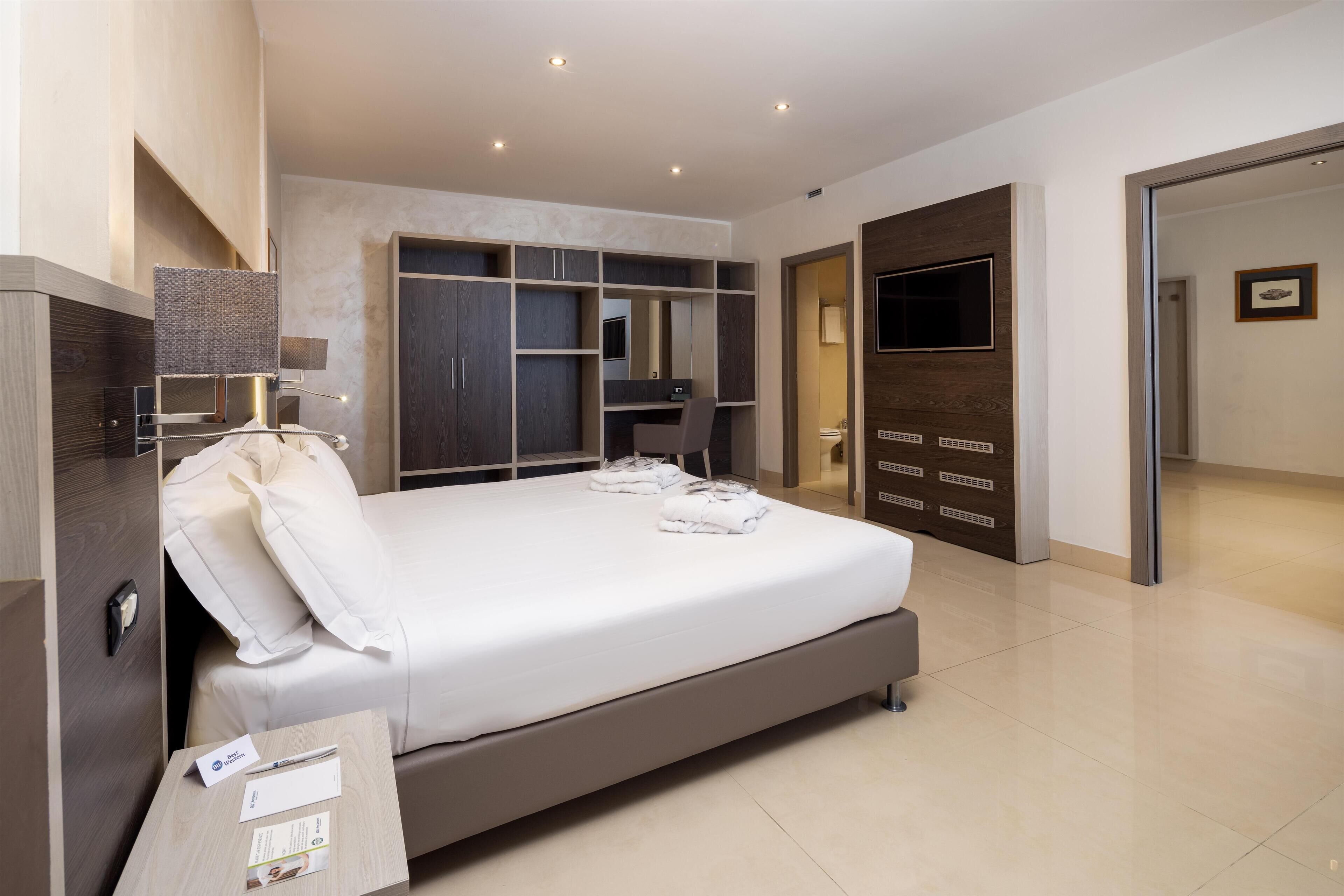 Une chambre d’hôtel moderne dotée d’un grand lit, d’une armoire intégrée et d’un téléviseur à écran plat.