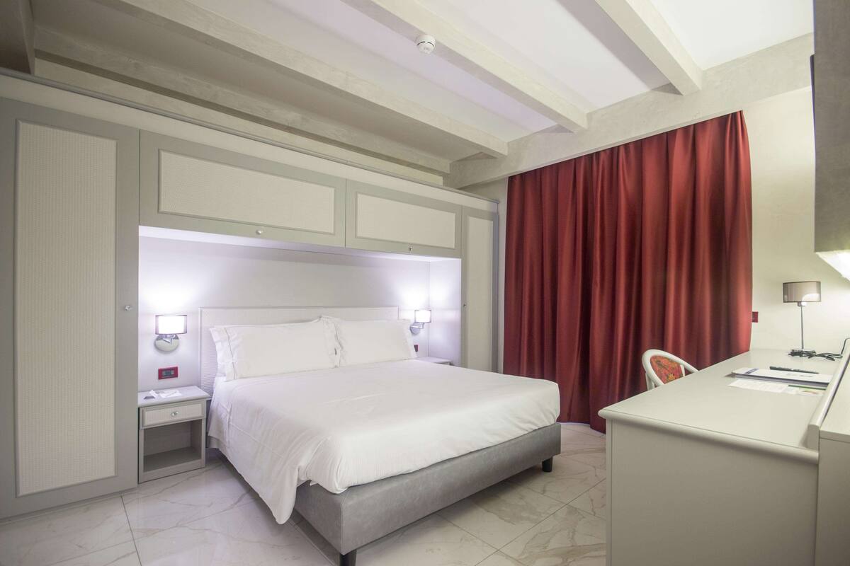 Ein Hotelzimmer mit Bett, Nachttischen, Schreibtisch und Stuhl.