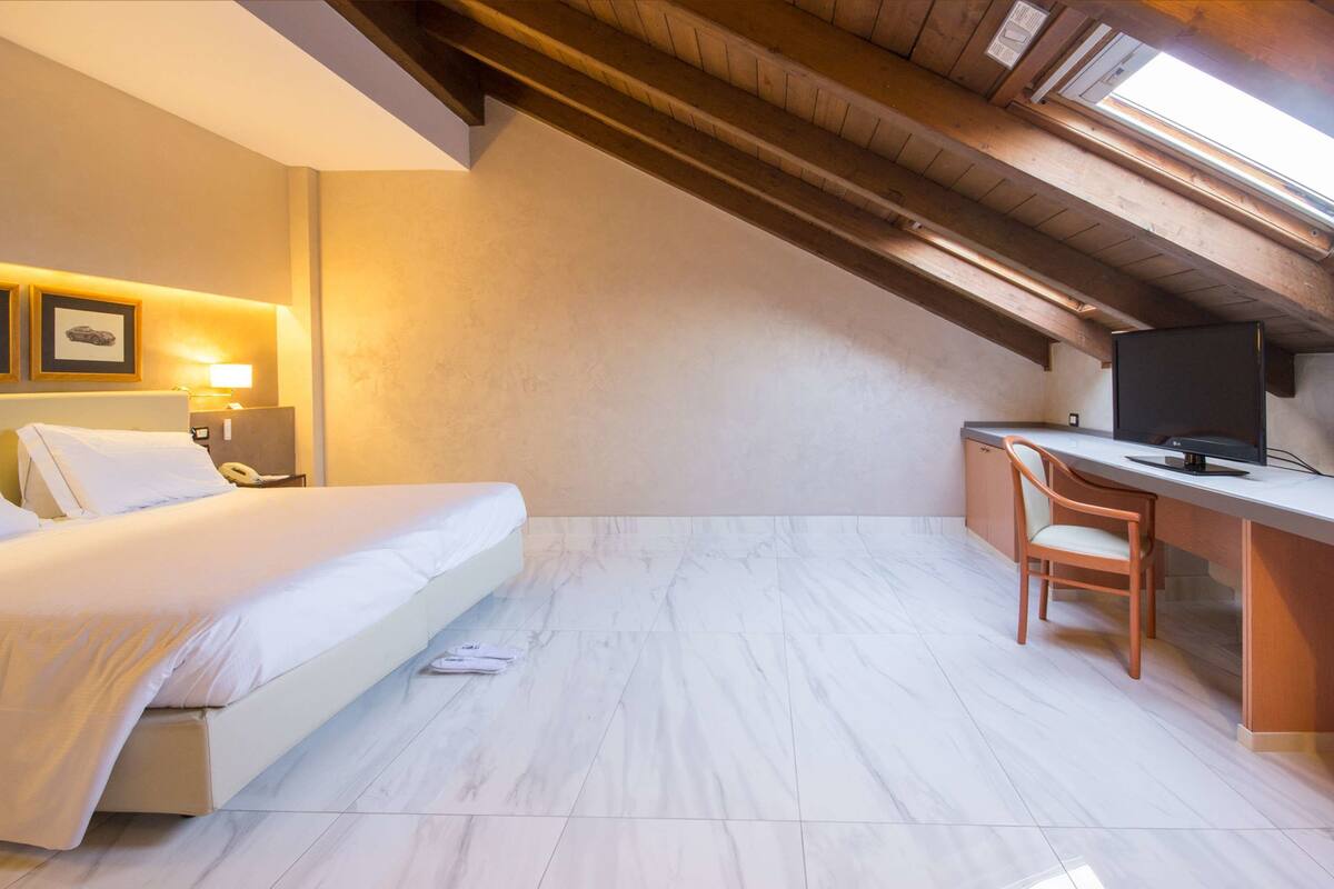 Ein Hotelzimmer mit Bett, Schreibtisch, Stuhl und Fernseher.