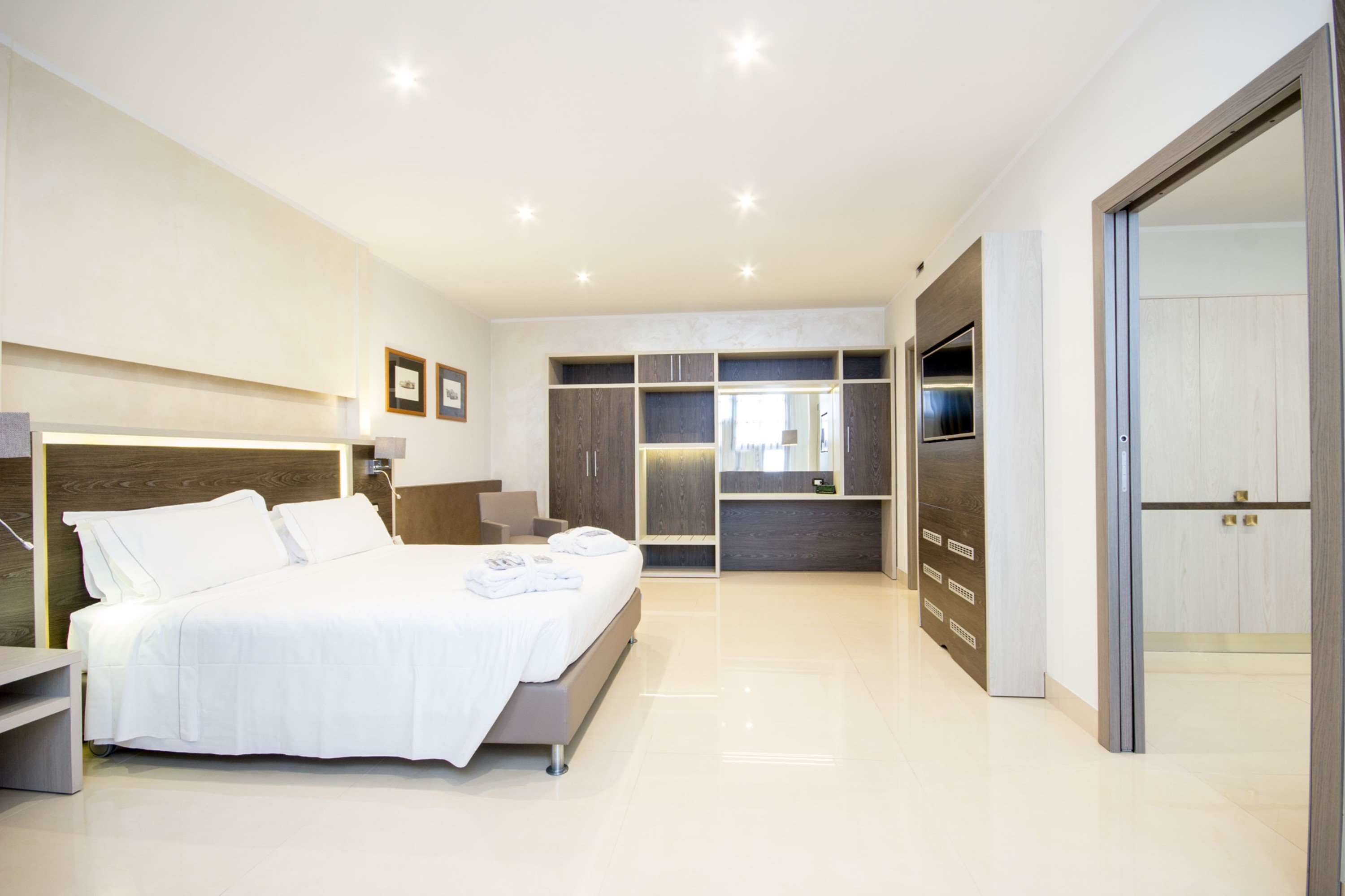 Un dormitorio moderno con una cama grande, armario empotrado y televisor.