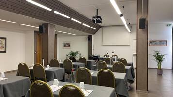 A conference room with tables and chairs, a projector, and a screen.