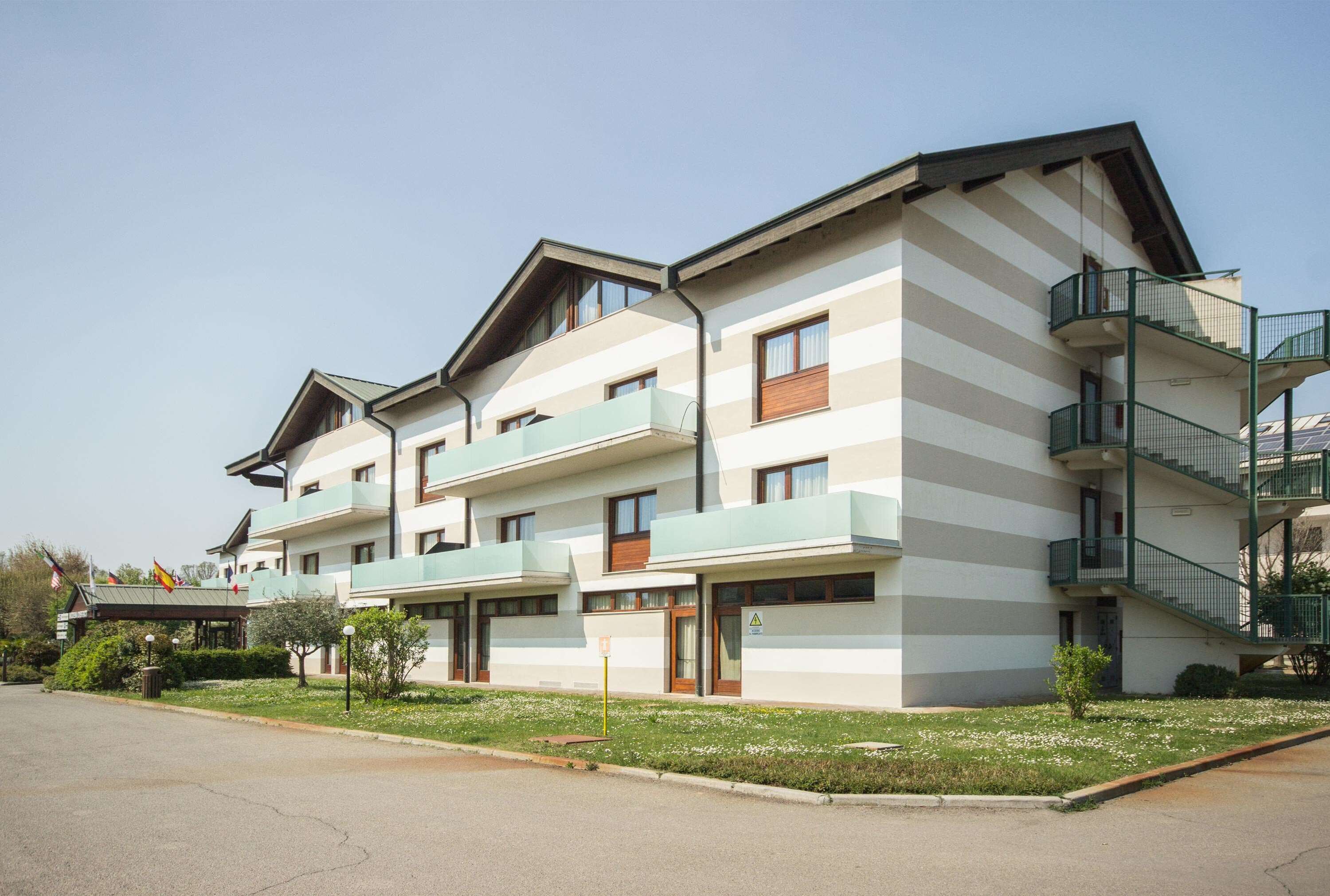 A multi-story hotel with a modern design, featuring balconies and a central courtyard.