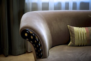 Ein beiges Sofa mit einem gestreiften Kissen und einem schwarz-gelb gemusterten Hocker.