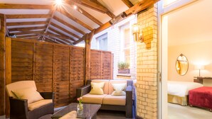 A cozy outdoor seating area with wicker furniture, a wooden ceiling, and a brick wall.