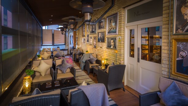 A cozy lounge area with wicker furniture, a brick wall, and framed artwork.