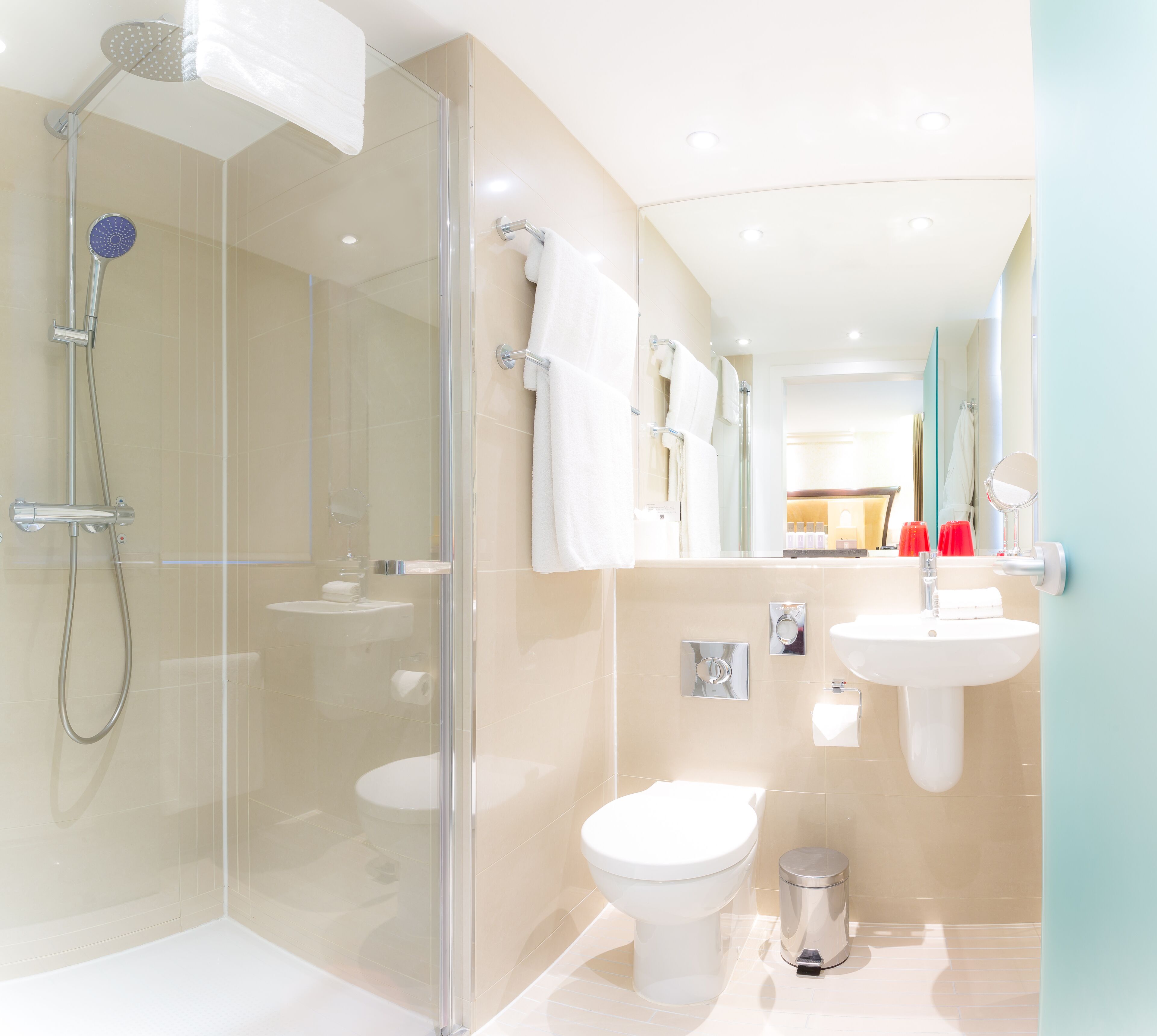 A modern bathroom with a glass-enclosed shower, a toilet, a sink, and a mirror.