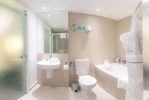 Ein modernes Badezimmer mit Duschkabine aus Glas, Waschbecken in Weiß, Toilette und Badewanne.