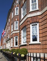 A row of red brick buildings with white windows and a British flag.
