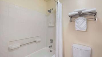 Une salle de bain équipée d’une baignoire, d’une douche, de toilettes et d’un porte-serviettes avec des serviettes pliées.