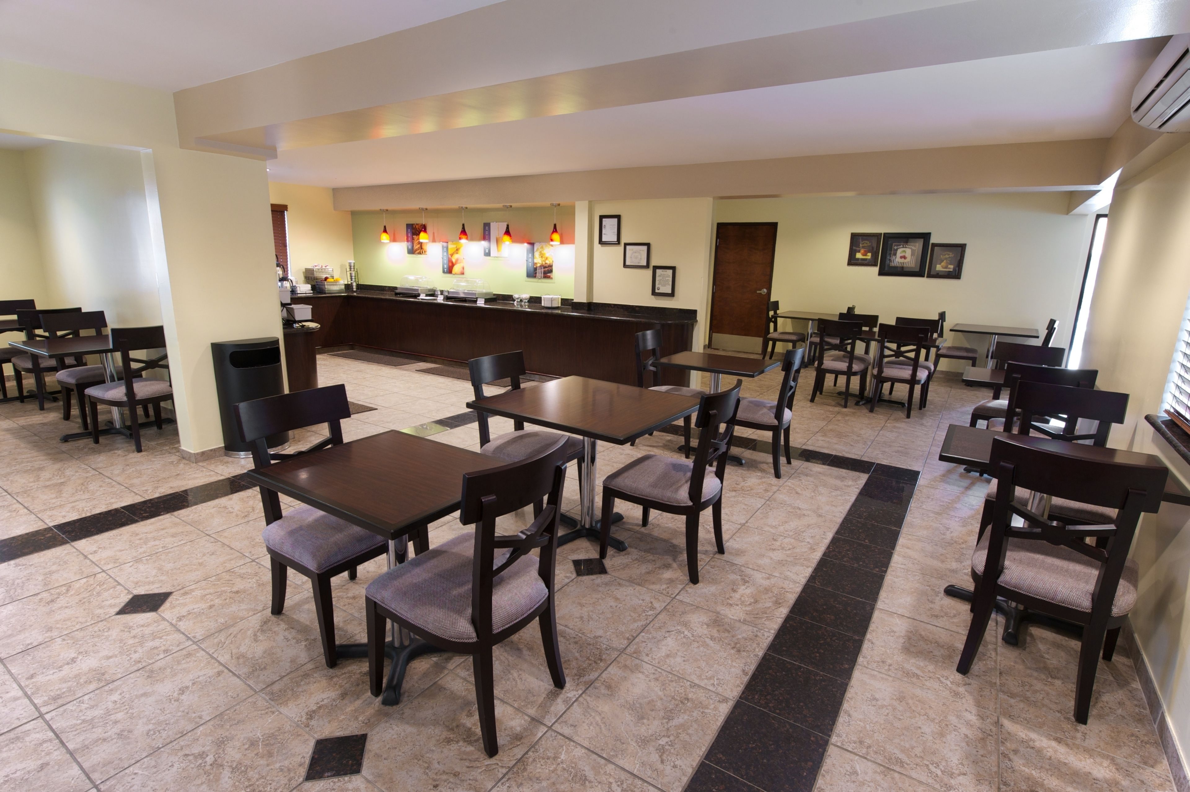 Comedor de hotel con varias mesas y sillas, una barra con el menú y cuadros en las paredes.