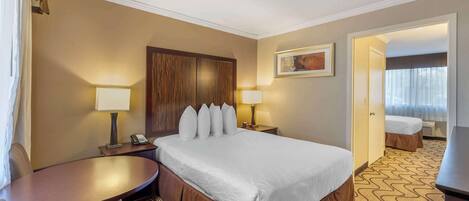 A hotel room with a large bed, two bedside tables with lamps, a small round table, and a chair.