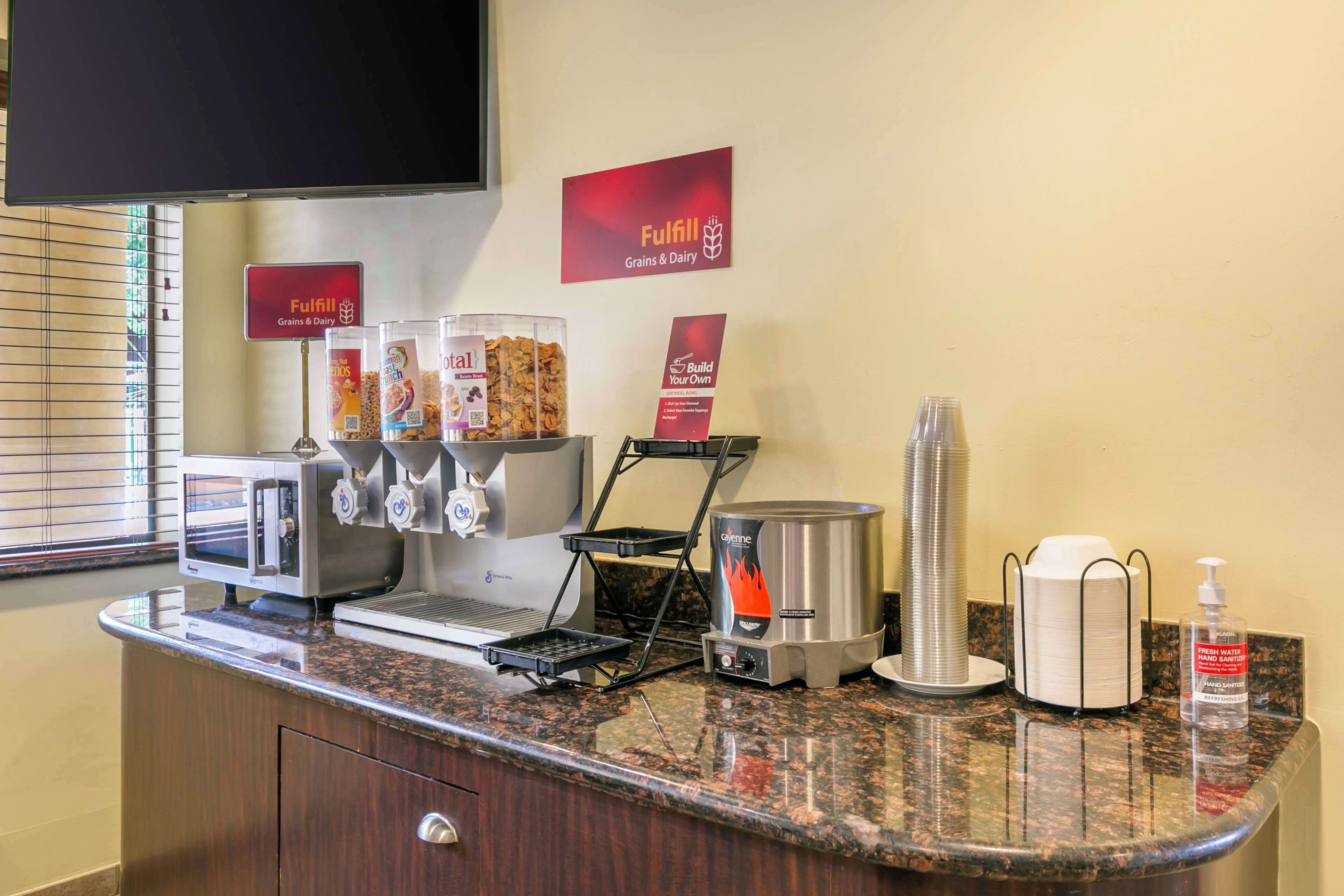 A self-service breakfast area with a coffee machine, cereal dispensers, and a hot beverage station.
