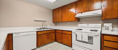 A kitchen with wooden cabinets, a dishwasher, a stove, and a coffee maker.